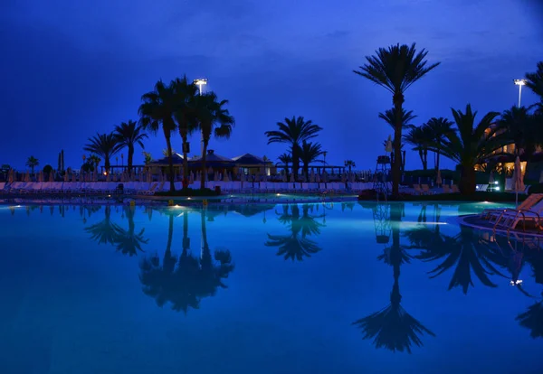 O céu azul escuro noite com uma piscina resort — Fotografia de Stock