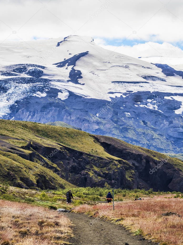 Couple of hikers with backpacks on the trail overlooking the mountains, Iceland
