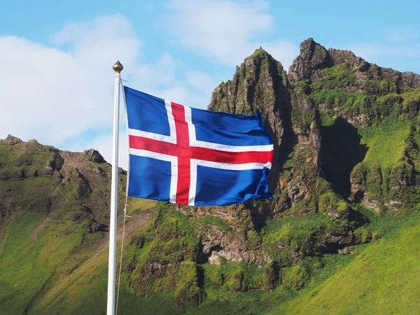 Flaga Islandii na tle zielonych gór i błękitnego nieba — Zdjęcie stockowe