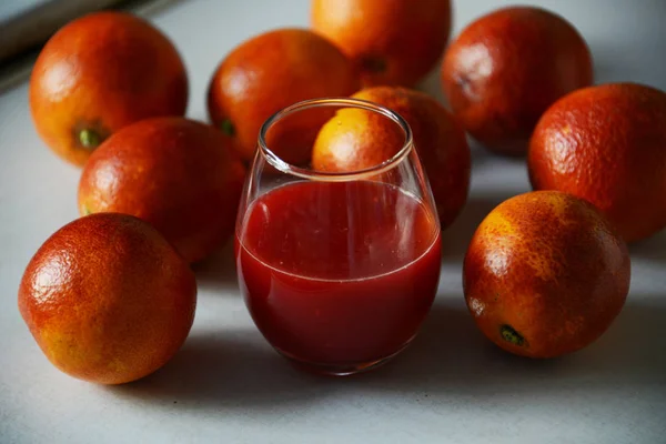 Taze meyve suyu ile bir cam etrafında kırmızı Sicilyalı portakallar