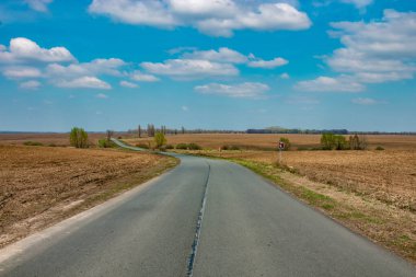 Issız bir yol. Beyaz bulutlu açık mavi gökyüzü. Dönüş yolu