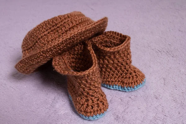 Knitted hat and boots. Knitted shoes and clothes. Booties for babies.