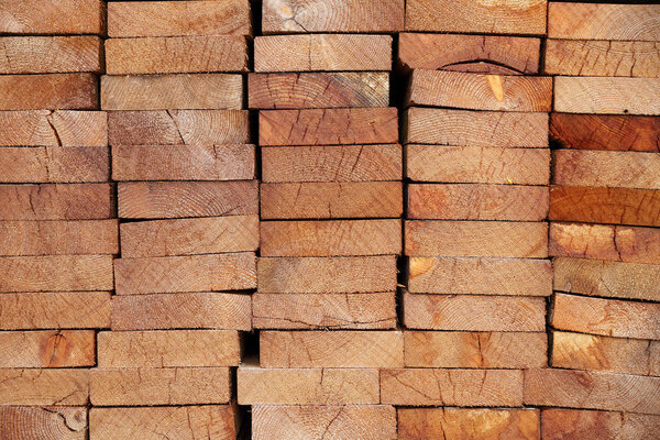 Pattern of stacked rectangular wooden beam timber at sawmill lumberyard