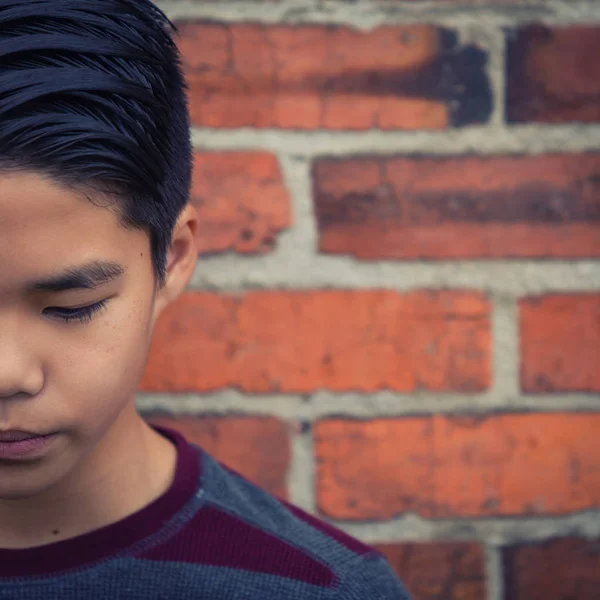 Artistic portrait of sad teenage asian boy looking downward.  Intentionally cropped half of face for effect and to create open space for text. — Stock Photo, Image