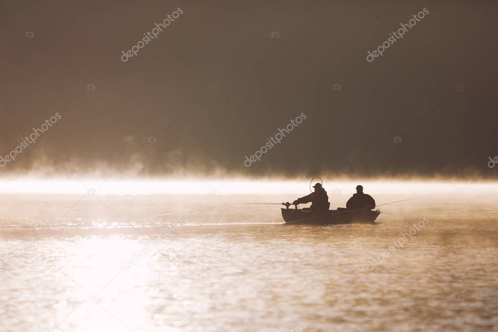 Silhouette of fishermen on lake at dawn