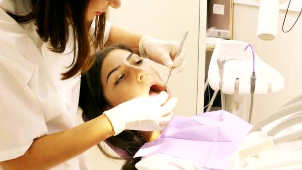 Dentist at work in dental unit with a young woman patient — Stock Video