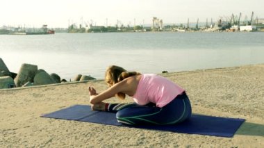 Kadın plajda yoga yapıyor.