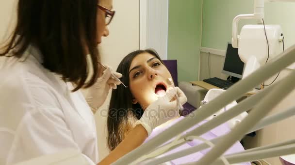 Οδοντίατρος στο έργο στην οδοντιατρική μονάδα με μια νεαρή γυναίκα ασθενή — Αρχείο Βίντεο
