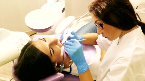 Dentist at work in dental unit with a young woman patient — Stock Video