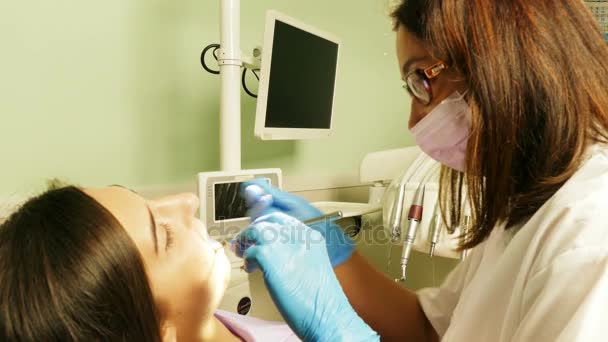 Dentist at work in dental unit with a young woman patient — Stock Video