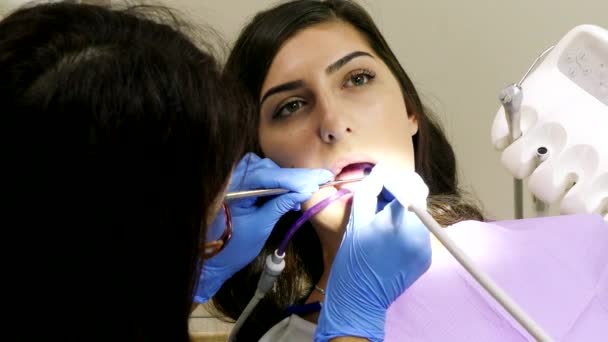 Dentista en el trabajo en la unidad dental con una paciente joven — Vídeos de Stock