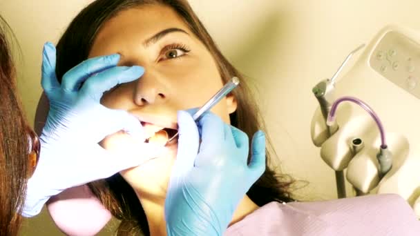 Dentista en el trabajo en la unidad dental con una paciente joven — Vídeos de Stock