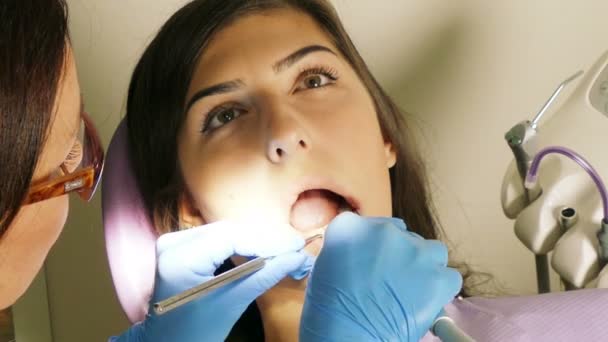 Dentista en el trabajo en la unidad dental con una paciente joven — Vídeos de Stock