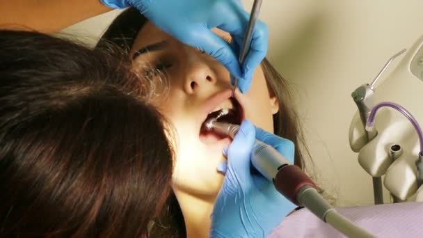 Dentist at work in dental unit with a young woman patient — Stock Video