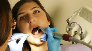 Dişçi diş ünitesi bir genç kadın hasta ile çalışmak