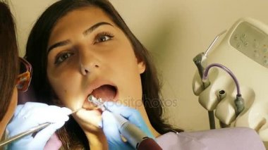 Dişçi diş ünitesi bir genç kadın hasta ile çalışmak