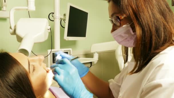 Dentista no trabalho em unidade dentária com uma jovem paciente — Vídeo de Stock