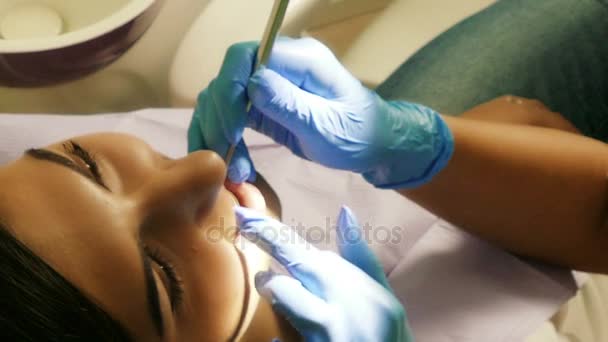 Стоматолог на роботі в стоматологічному відділенні з молодою жінкою-пацієнтом — стокове відео