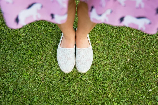 Hierba verde y pies femeninos en zapatos de verano de tela —  Fotos de Stock