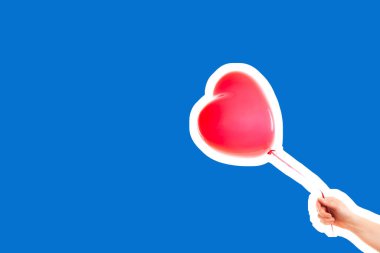 Kadın eli kırmızı kauçuk, şişme kalp şeklinde balon tutuyor. Aşk, ilişki, sevgililer günü ve doğum günü kutlaması konsepti. Boş kopya alanı olan dergi tarzı moda kolajı