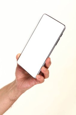 İnsan eli, avucunda boş bir krom ekran olan modern bir akıllı telefonu tutar. Teknoloji ve reklam kavramı. Ayrıntılı yakın çekim stüdyo çekimi soyut beyaz arka planda izole