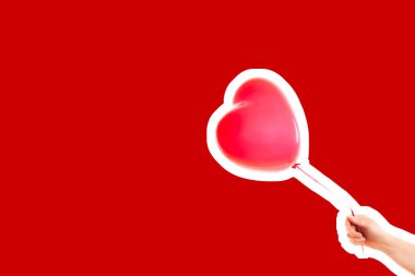 Kadın eli kırmızı kauçuk, şişme kalp şeklinde balon tutuyor. Aşk, ilişki, sevgililer günü ve doğum günü kutlaması konsepti. Boş kopya alanı olan dergi tarzı moda kolajı