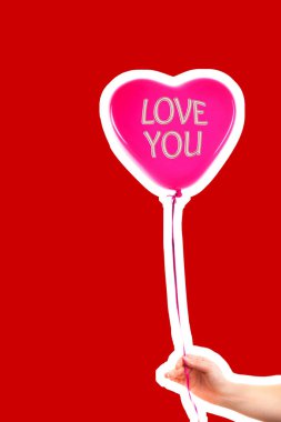Kadın eli kırmızı kauçuk, şişme kalp şeklinde balon tutuyor. Aşk, ilişki, sevgililer günü ve doğum günü kutlaması konsepti. Boş kopya alanı olan dergi tarzı moda kolajı