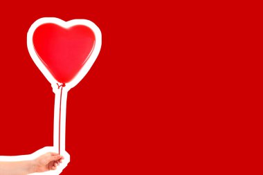 Kadın eli kırmızı kauçuk, şişme kalp şeklinde balon tutuyor. Aşk, ilişki, sevgililer günü ve doğum günü kutlaması konsepti. Boş kopya alanı olan dergi tarzı moda kolajı