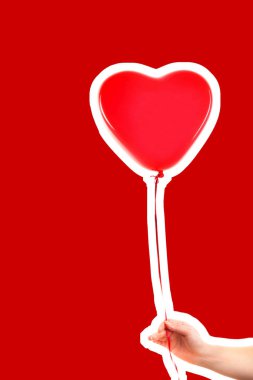 Kadın eli kırmızı kauçuk, şişme kalp şeklinde balon tutuyor. Aşk, ilişki, sevgililer günü ve doğum günü kutlaması konsepti. Boş kopya alanı olan dergi tarzı moda kolajı