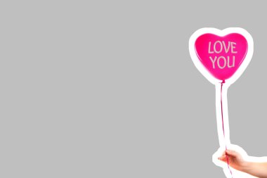 Kadın eli kırmızı kauçuk, şişme kalp şeklinde balon tutuyor. Aşk, ilişki, sevgililer günü ve doğum günü kutlaması konsepti. Boş kopya alanı olan dergi tarzı moda kolajı