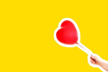 Kadın eli kırmızı kauçuk, şişme kalp şeklinde balon tutuyor. Aşk, ilişki, sevgililer günü ve doğum günü kutlaması konsepti. Boş kopya alanı olan dergi tarzı moda kolajı