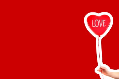 Kadın eli kırmızı kauçuk, şişme kalp şeklinde balon tutuyor. Aşk, ilişki, sevgililer günü ve doğum günü kutlaması konsepti. Boş kopya alanı olan dergi tarzı moda kolajı
