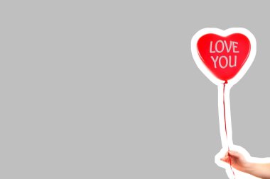 Kadın eli kırmızı kauçuk, şişme kalp şeklinde balon tutuyor. Aşk, ilişki, sevgililer günü ve doğum günü kutlaması konsepti. Boş kopya alanı olan dergi tarzı moda kolajı