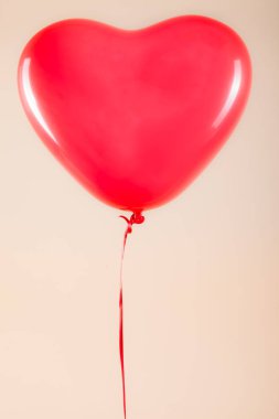 Kadın eli kırmızı kauçuk, şişme kalp şeklinde balon tutuyor. Aşk, ilişki, sevgililer günü ve doğum günü kutlaması konsepti. Stüdyo görüntüsü boş kopya alanı olan bulanık bir arkaplan üzerinde