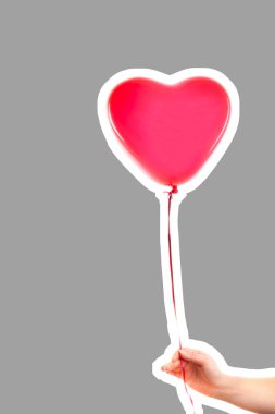 Kadın eli kırmızı kauçuk, şişme kalp şeklinde balon tutuyor. Aşk, ilişki, sevgililer günü ve doğum günü kutlaması konsepti. Boş kopya alanı olan dergi tarzı moda kolajı