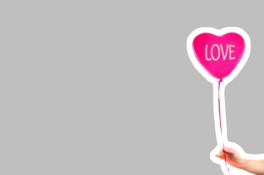 Kadın eli kırmızı kauçuk, şişme kalp şeklinde balon tutuyor. Aşk, ilişki, sevgililer günü ve doğum günü kutlaması konsepti. Boş kopya alanı olan dergi tarzı moda kolajı