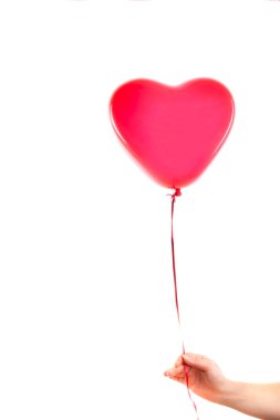 Kadın eli kırmızı kauçuk, şişme kalp şeklinde balon tutuyor. Aşk, ilişki, sevgililer günü ve doğum günü kutlaması konsepti. Stüdyo görüntüsü boş kopya alanı olan bulanık bir arkaplan üzerinde