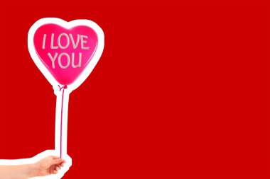 Kadın eli kırmızı kauçuk, şişme kalp şeklinde balon tutuyor. Aşk, ilişki, sevgililer günü ve doğum günü kutlaması konsepti. Boş kopya alanı olan dergi tarzı moda kolajı