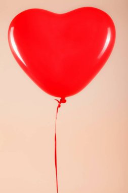 Kadın eli kırmızı kauçuk, şişme kalp şeklinde balon tutuyor. Aşk, ilişki, sevgililer günü ve doğum günü kutlaması konsepti. Stüdyo görüntüsü boş kopya alanı olan bulanık bir arkaplan üzerinde