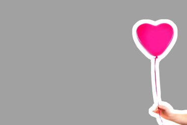 Kadın eli pembe kauçuk, şişme kalp şeklinde balon tutuyor. Aşk, ilişki, sevgililer günü ve doğum günü kutlaması konsepti. Boş kopya alanı olan dergi tarzı moda kolajı