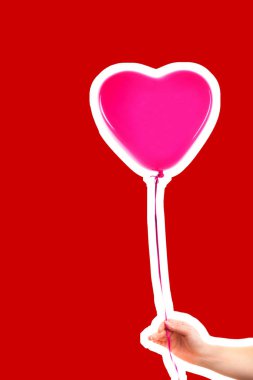 Kadın eli pembe kauçuk, şişme kalp şeklinde balon tutuyor. Aşk, ilişki, sevgililer günü ve doğum günü kutlaması konsepti. Boş kopya alanı olan dergi tarzı moda kolajı