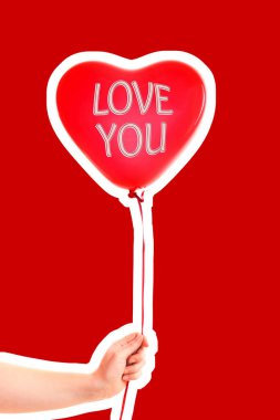 Kadın eli kırmızı kauçuk, şişme kalp şeklinde balon tutuyor. Aşk, ilişki, sevgililer günü ve doğum günü kutlaması konsepti. Boş kopya alanı olan dergi tarzı moda kolajı