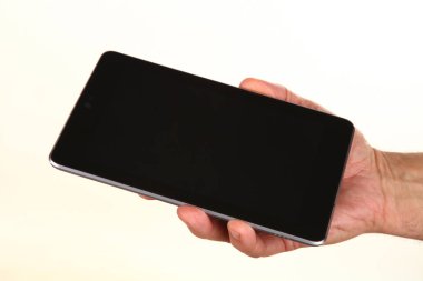 İnsan eli, avucunda boş bir krom ekran olan modern bir akıllı telefonu tutar. Teknoloji ve reklam kavramı. Ayrıntılı yakın çekim stüdyo çekimi soyut beyaz arka planda izole