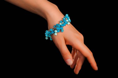 Güzel bir el yapımı mücevher bileziği. Renkli parlak boncuklar ve nötr manikürlü gevşek bir kadın bileği. Moda ve el işi aksesuarları. Yumuşak seçici odaklı yakın plan