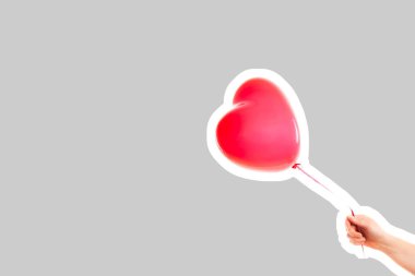 Kadın eli kırmızı kauçuk, şişme kalp şeklinde balon tutuyor. Aşk, ilişki, sevgililer günü ve doğum günü kutlaması konsepti. Boş kopya alanı olan dergi tarzı moda kolajı
