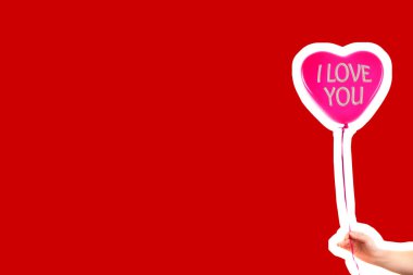 Kadın eli kırmızı kauçuk, şişme kalp şeklinde balon tutuyor. Aşk, ilişki, sevgililer günü ve doğum günü kutlaması konsepti. Boş kopya alanı olan dergi tarzı moda kolajı