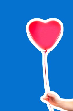 Kadın eli kırmızı kauçuk, şişme kalp şeklinde balon tutuyor. Aşk, ilişki, sevgililer günü ve doğum günü kutlaması konsepti. Boş kopya alanı olan dergi tarzı moda kolajı