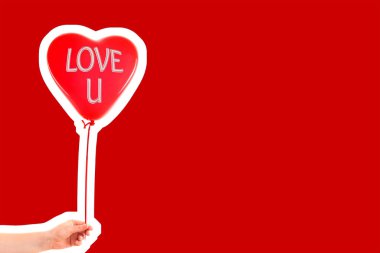 Kadın eli kırmızı kauçuk, şişme kalp şeklinde balon tutuyor. Aşk, ilişki, sevgililer günü ve doğum günü kutlaması konsepti. Boş kopya alanı olan dergi tarzı moda kolajı