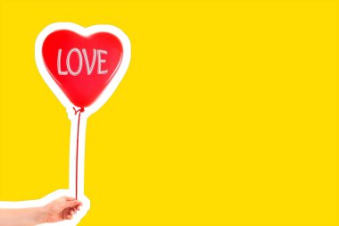 Kadın eli kırmızı kauçuk, şişme kalp şeklinde balon tutuyor. Aşk, ilişki, sevgililer günü ve doğum günü kutlaması konsepti. Boş kopya alanı olan dergi tarzı moda kolajı