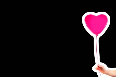 Kadın eli pembe kauçuk, şişme kalp şeklinde balon tutuyor. Aşk, ilişki, sevgililer günü ve doğum günü kutlaması konsepti. Boş kopya alanı olan dergi tarzı moda kolajı